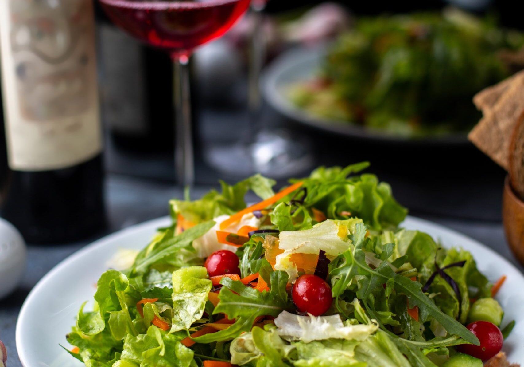 a front view greens vegetables sliced along with red wine inside white plate